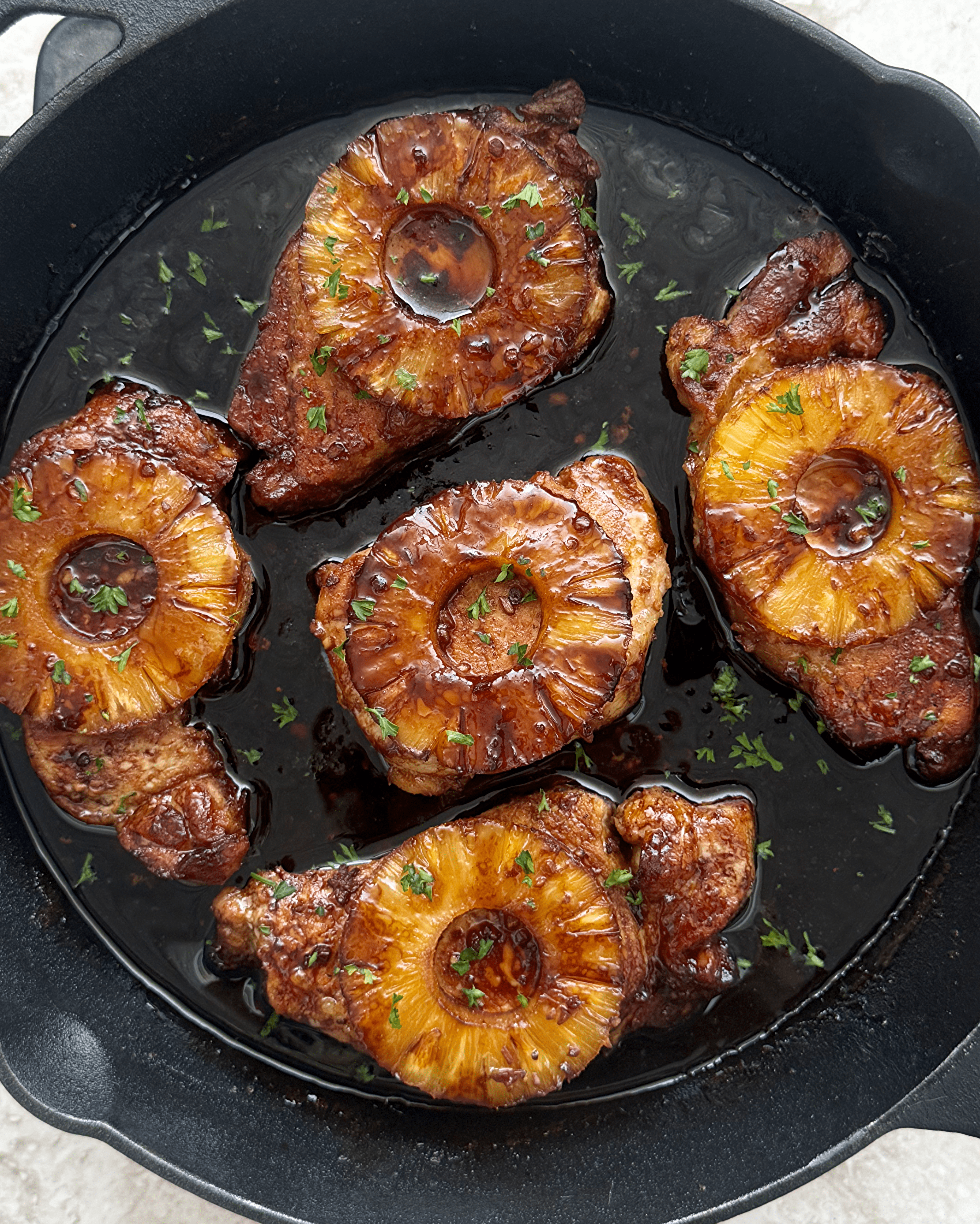 overhead shot of Baked Pineapple Teriyaki Pork Chops in a black cast iron skillet