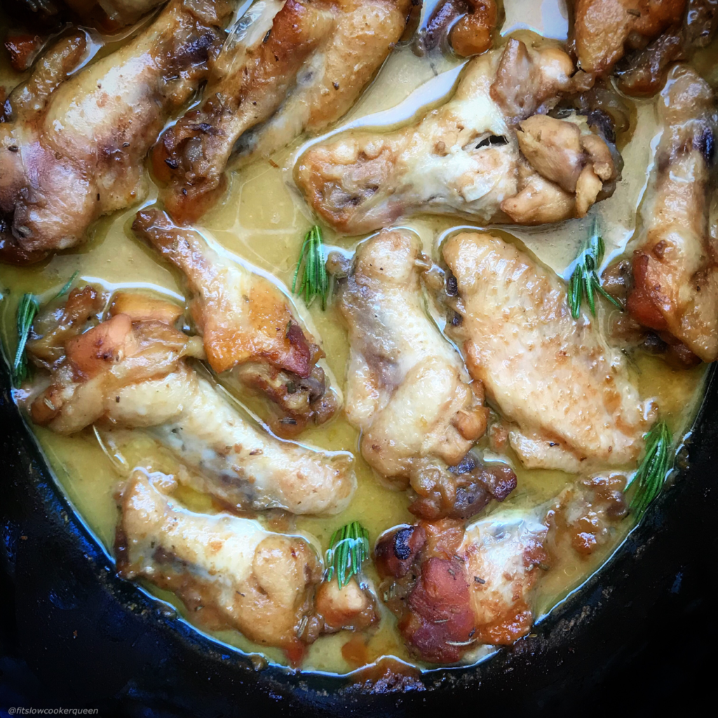 overhead shot of cooked honey mustard chicken wings in a black slow cooker