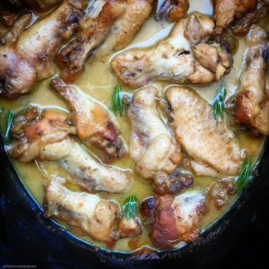 overhead shot of cooked honey mustard chicken wings in a black slow cooker