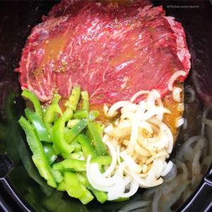 overhead shot of uncooked cilantro lime beef in a black slow cooker