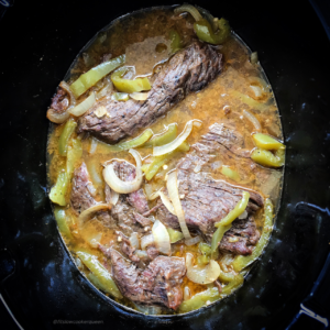 overhead shot of uncooked cilantro lime beef in a black slow cooker