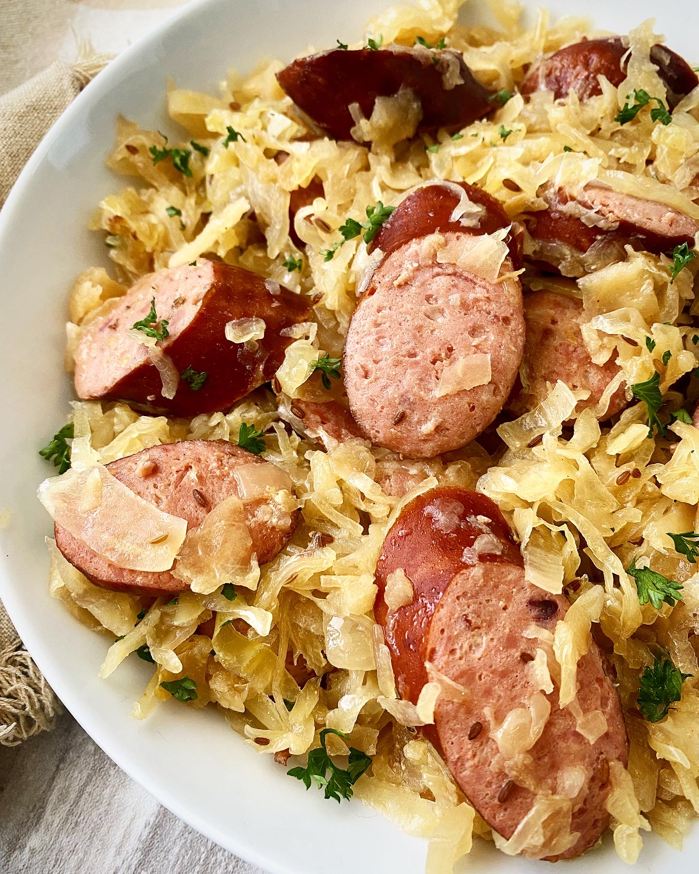 close up side view of Sausage & Sauerkraut in a white bowl