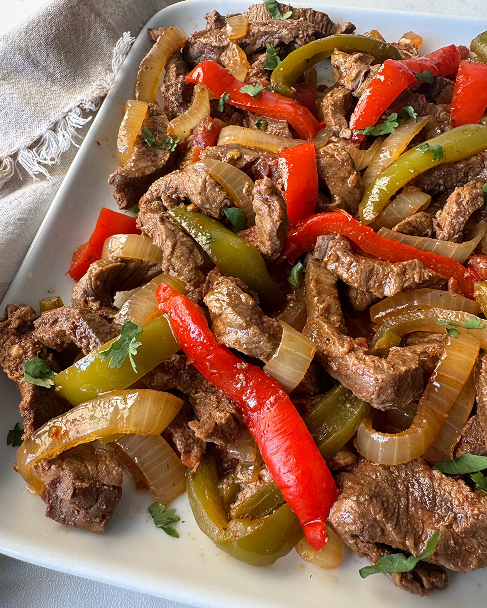 overhead shot of cooked steak fajitas on a white plate