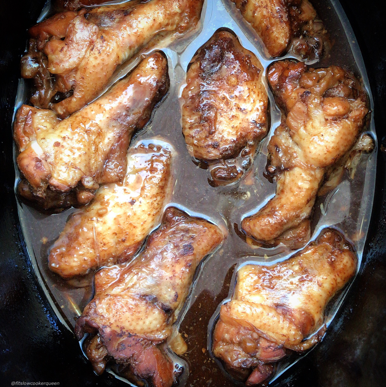 overhead after shot of cooked teriyaki chicken wings in a black slow cooker