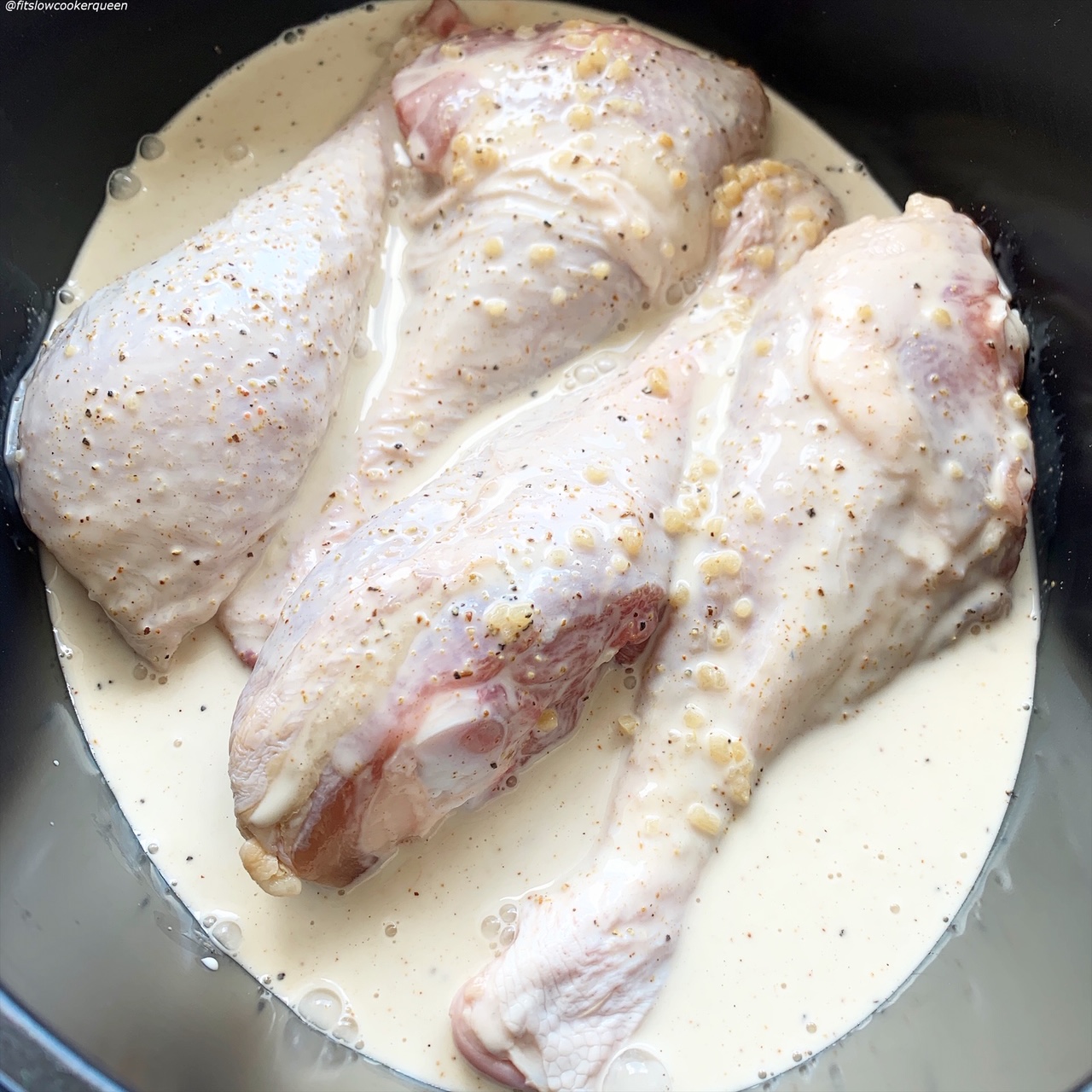 raw turkey legs in the slow cooker covered in coconut sauce