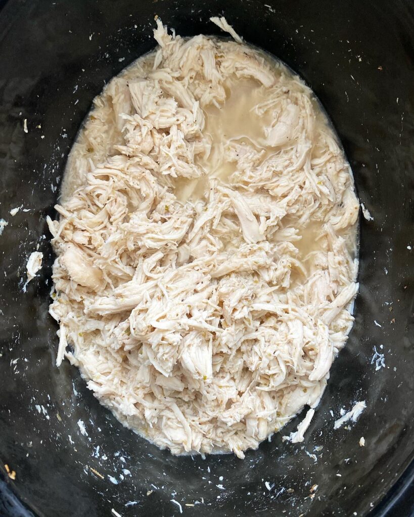 overhead shot of cooked Greek shredded chicken in the slow cooker