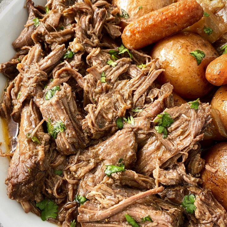 close up shot of of cooked crockpot cumin beef pot roast on a white plate