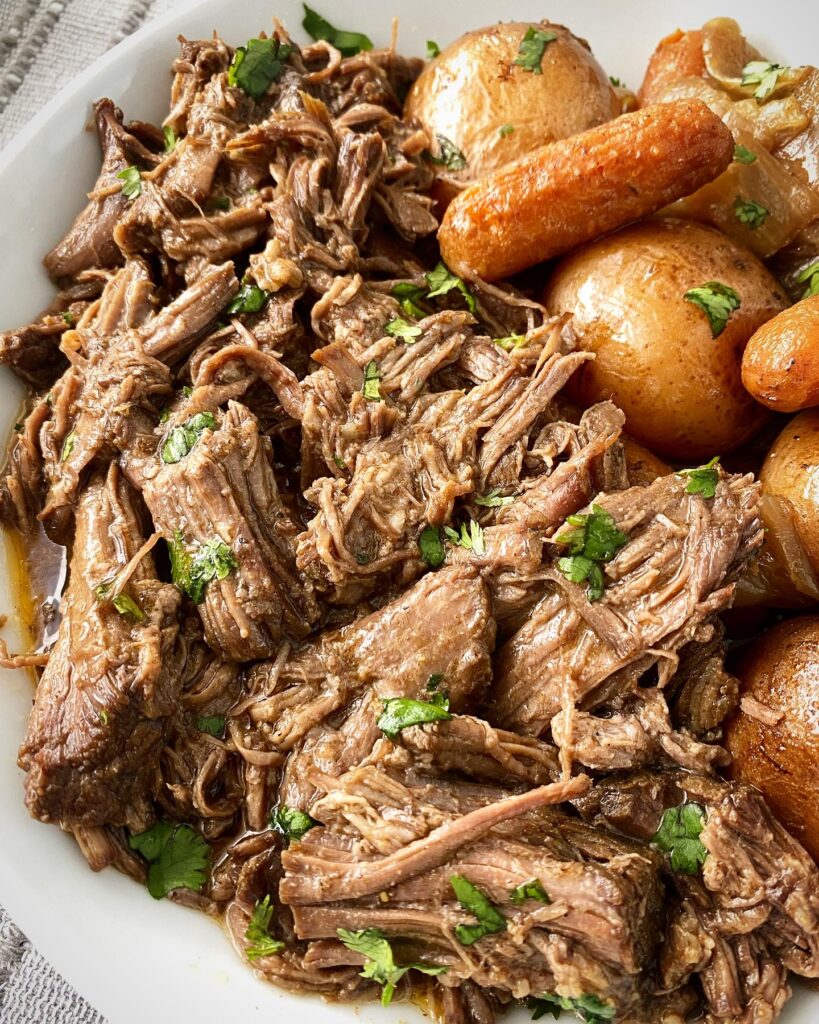 close up shot of of cooked crockpot cumin beef pot roast on a white plate