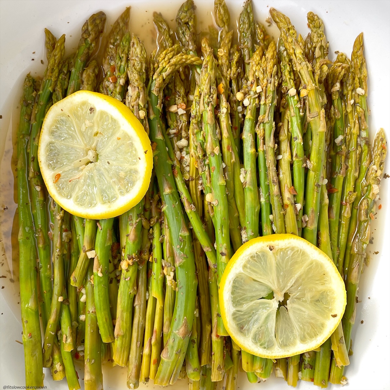 close up of cooked asparagus in a bowl topped with seasonings and garlic
