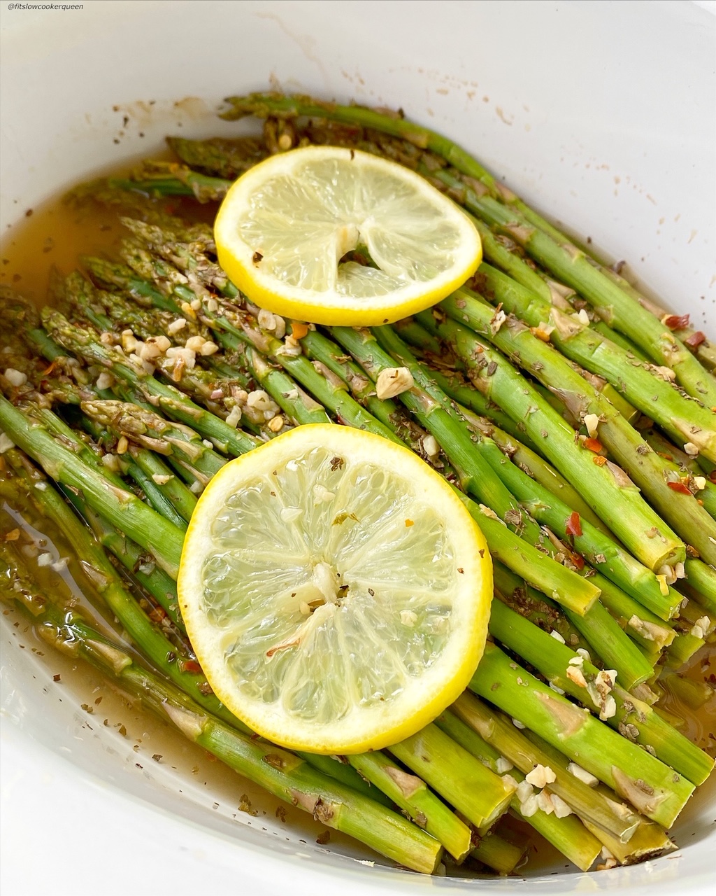 another close up of cooked asparagus in a bowl topped with seasonings and garlic