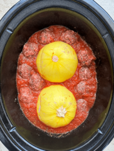overhead shot of uncooked spaghetti squash meatballs in a black slow cooker
