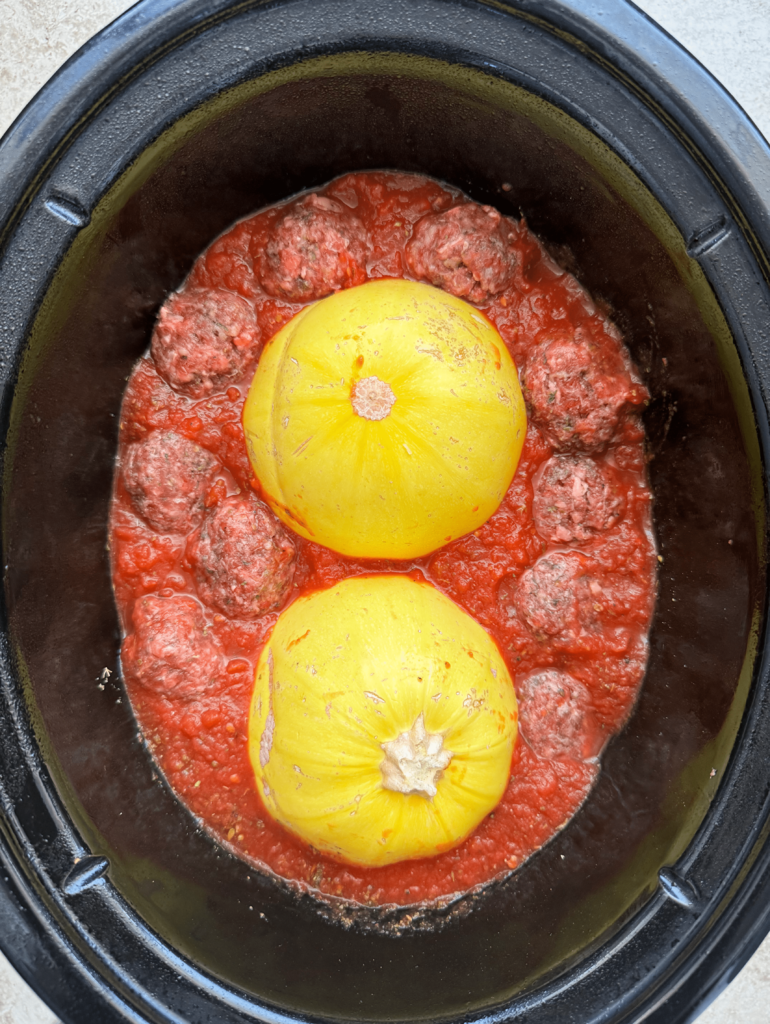 overhead shot of uncooked spaghetti squash meatballs in a black slow cooker