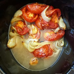 overhead shot of roasted veggies in broth in a black slow cooker
