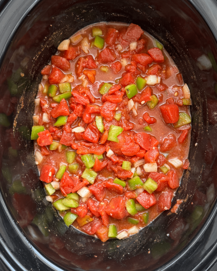 overhead shot of uncooked slow cooker shakshuka in a black slow cooker
