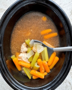 overhead shot of cooked Crockpot Copycat Benihana Chicken Onion Soup in a black slow cooker