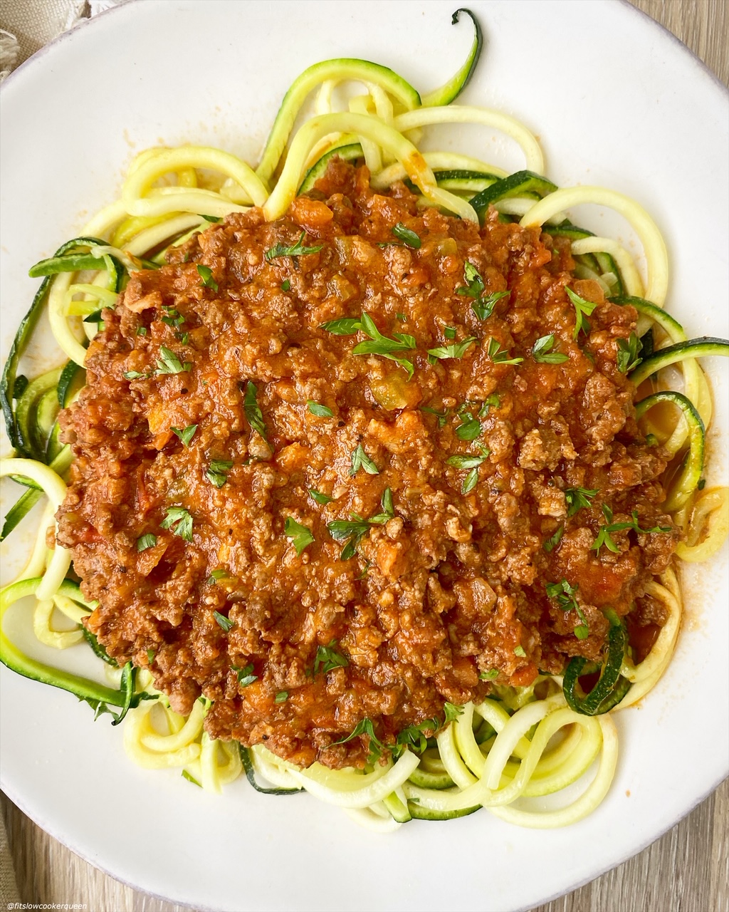 cooked bolognese served over a plate of zucchini zoodles