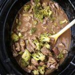 overhead shot of cooked beef and broccoli in a black slow cooker
