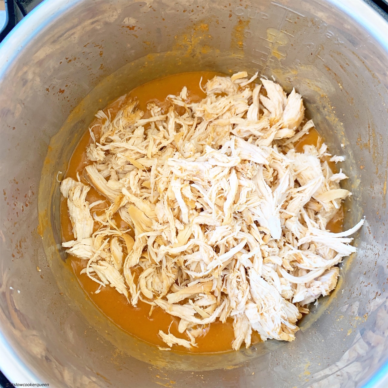 shredded chicken in the pressure cooker after being cooked in the spicy honey mustard sauce for slow cooker/instant pot spicy honey mustard chicken
