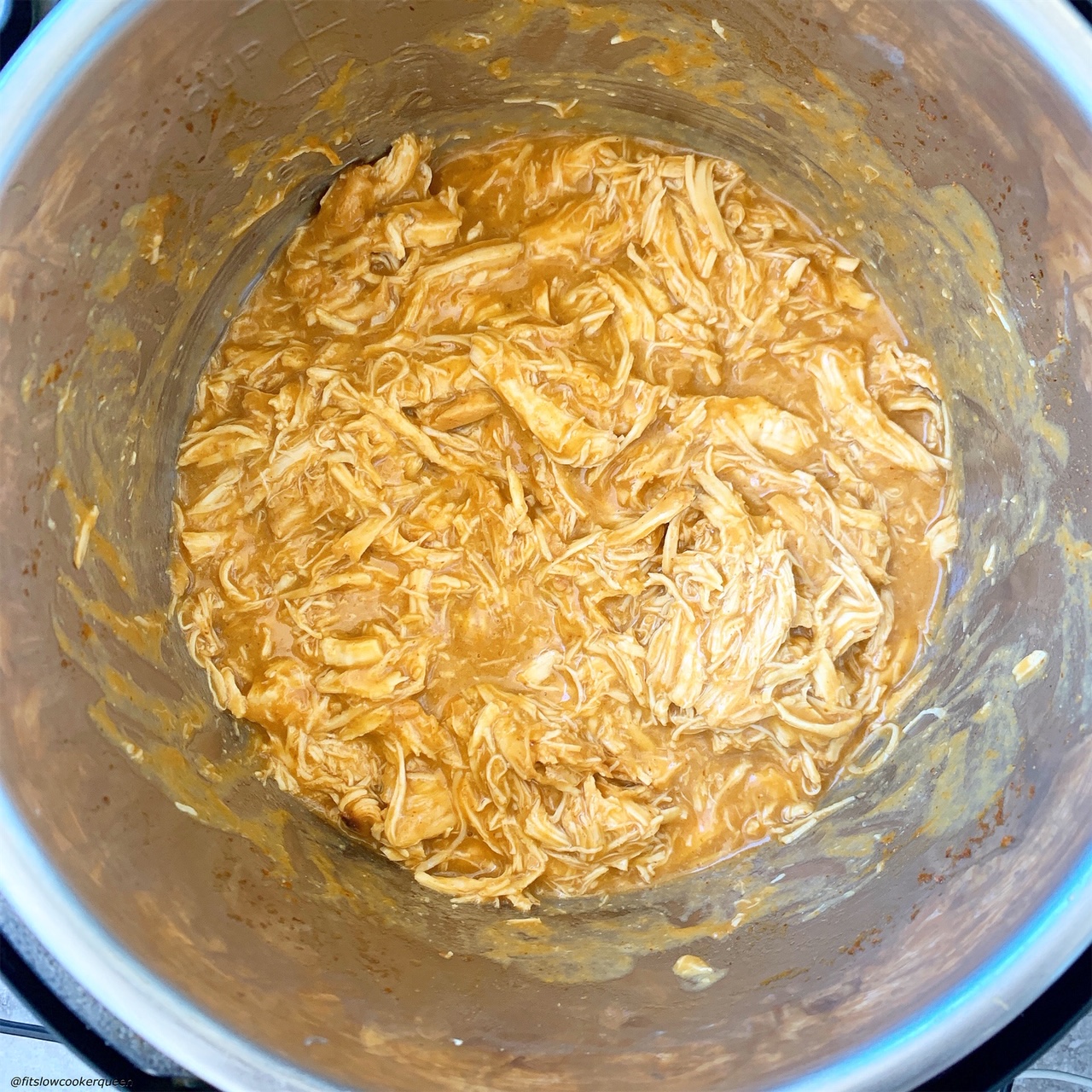 shredded chicken in the pressure cooker after being cooked in the spicy honey mustard sauce for slow cooker/instant pot spicy honey mustard chicken