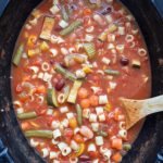 overhead shot of cooked minestrone soup in a black slow cooker
