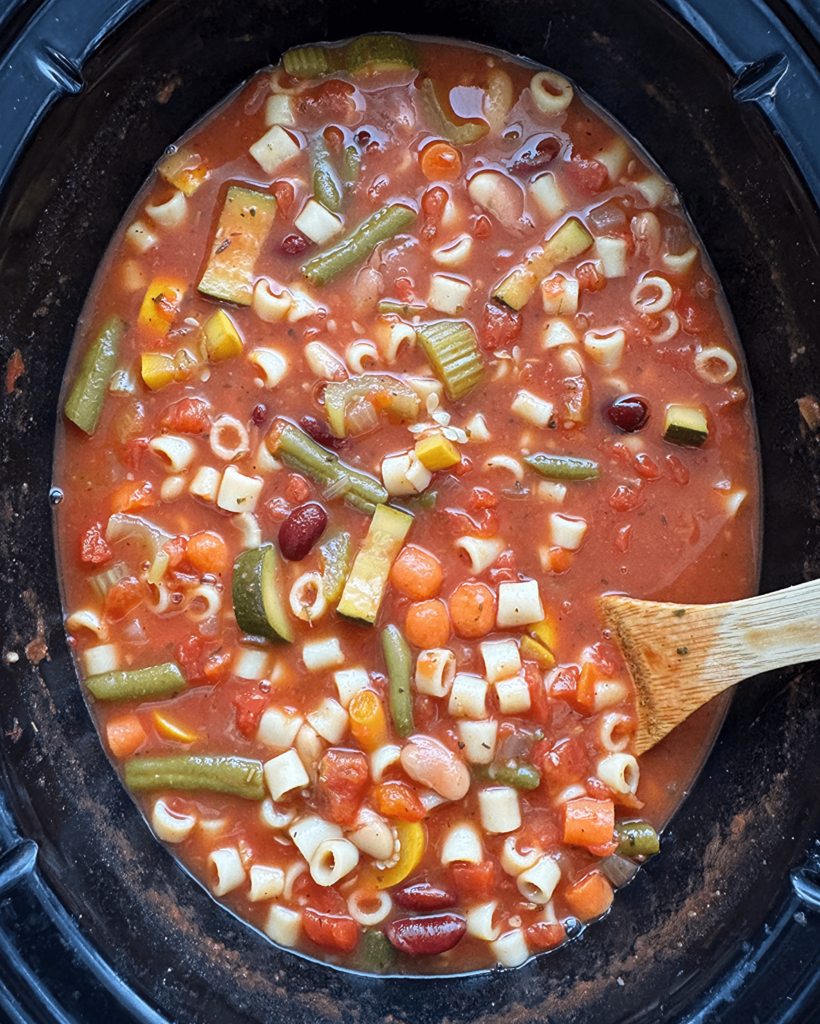 overhead shot of cooked minestrone soup in a black slow cooker