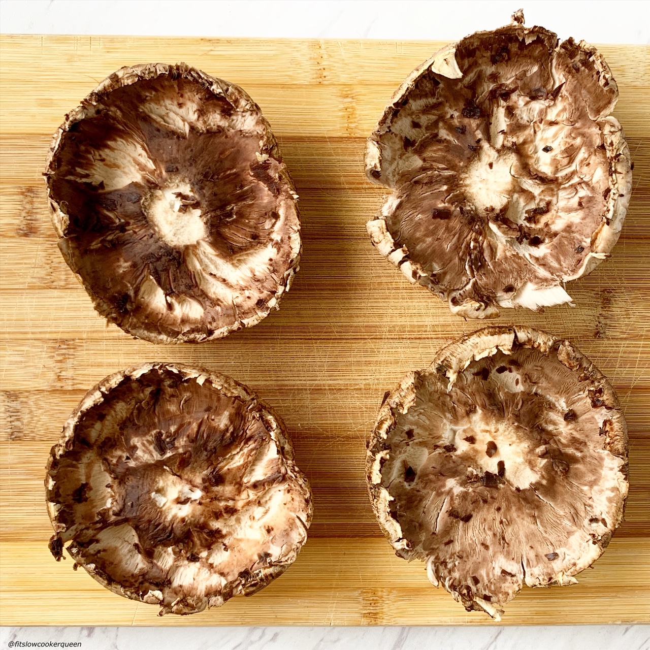 4 large portobello mushrooms cleaned with gills removed on a cutting board