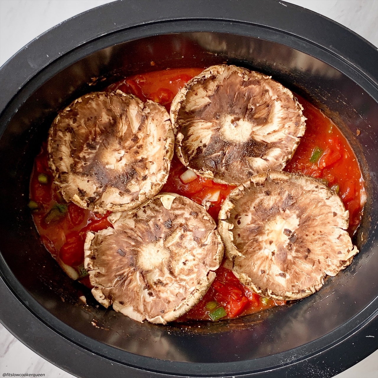 4 large portobello mushrooms in the slow cooker on top of tomato sauce