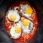 close up of cooked eggs added on top of cooked portobello mushrooms in the slow cooke