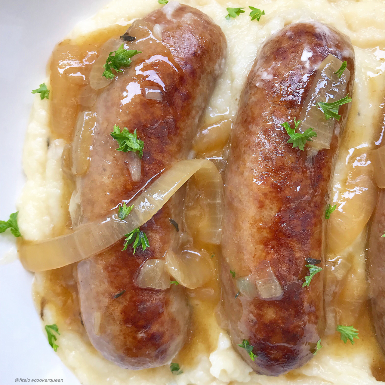 overhead shot of cooked bangers on a bed of mashed potatoes with gravy