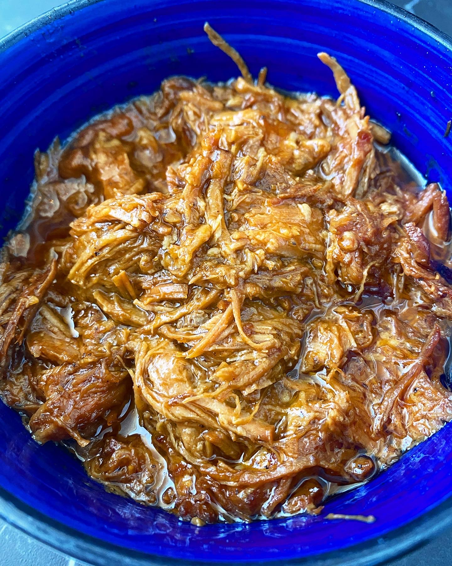 close up of shredded BBQ pulled pork in a blue bowl