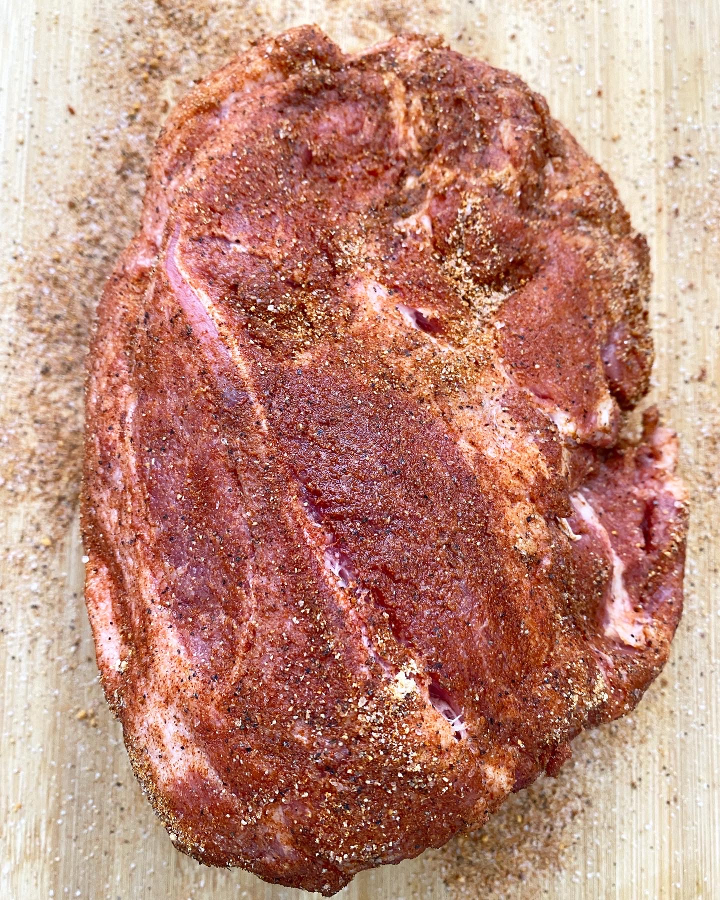 overhead shot of seasoned pork butt on a wooden cutting board