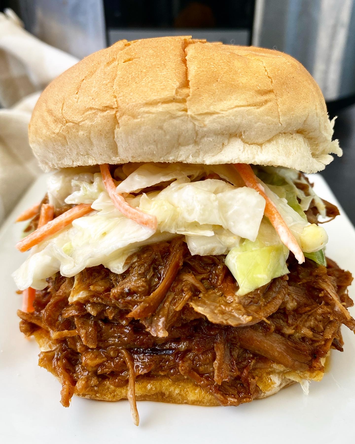 close up shot of shredded pulled pork on a bun topped with coleslaw