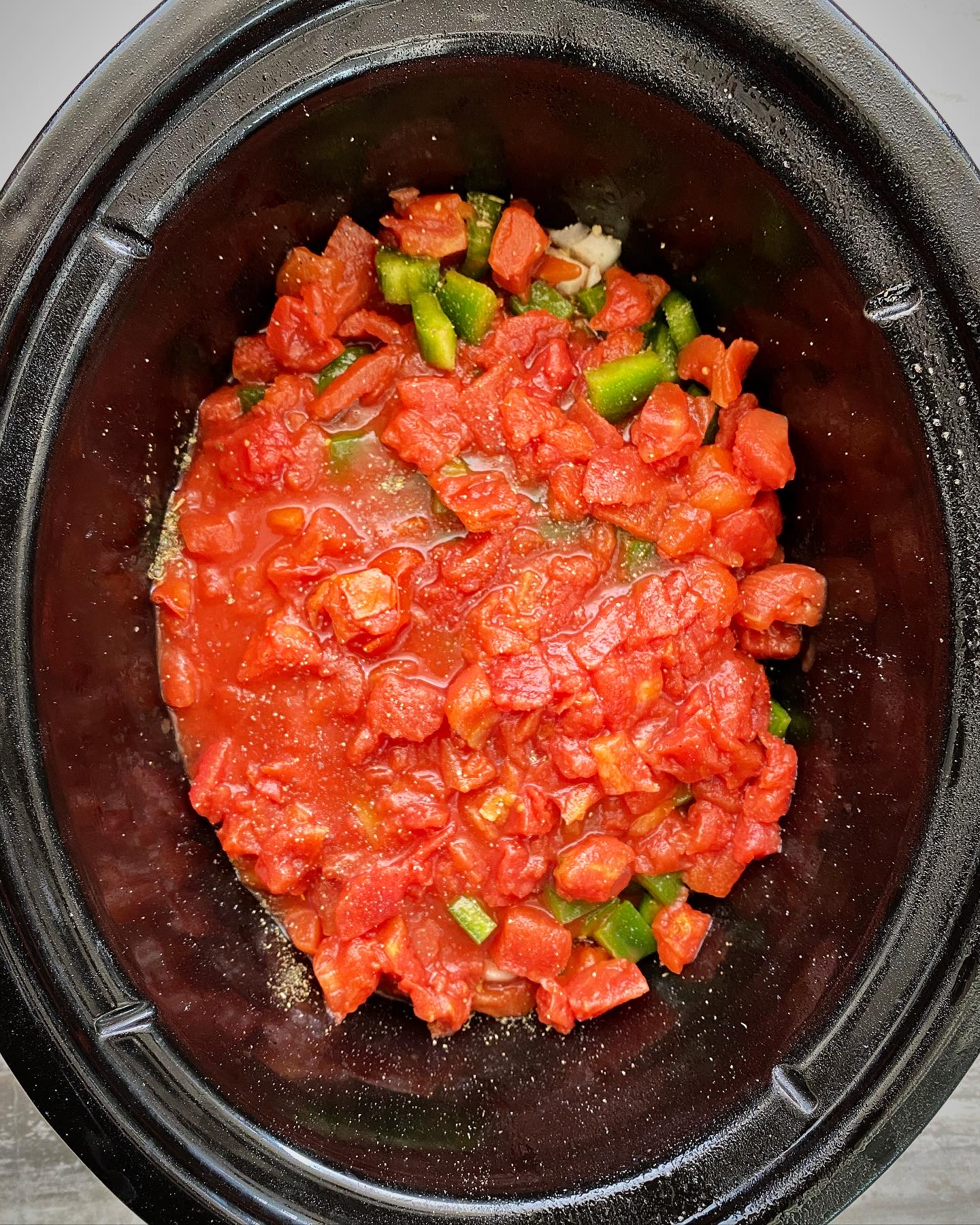 overhead shot of uncooked Mediterranean Salmon in a black slow cooker