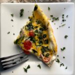 overhead shot of a slice of Slow Cooker Egg White Fritatta on a white plate garnished with fresh parsley