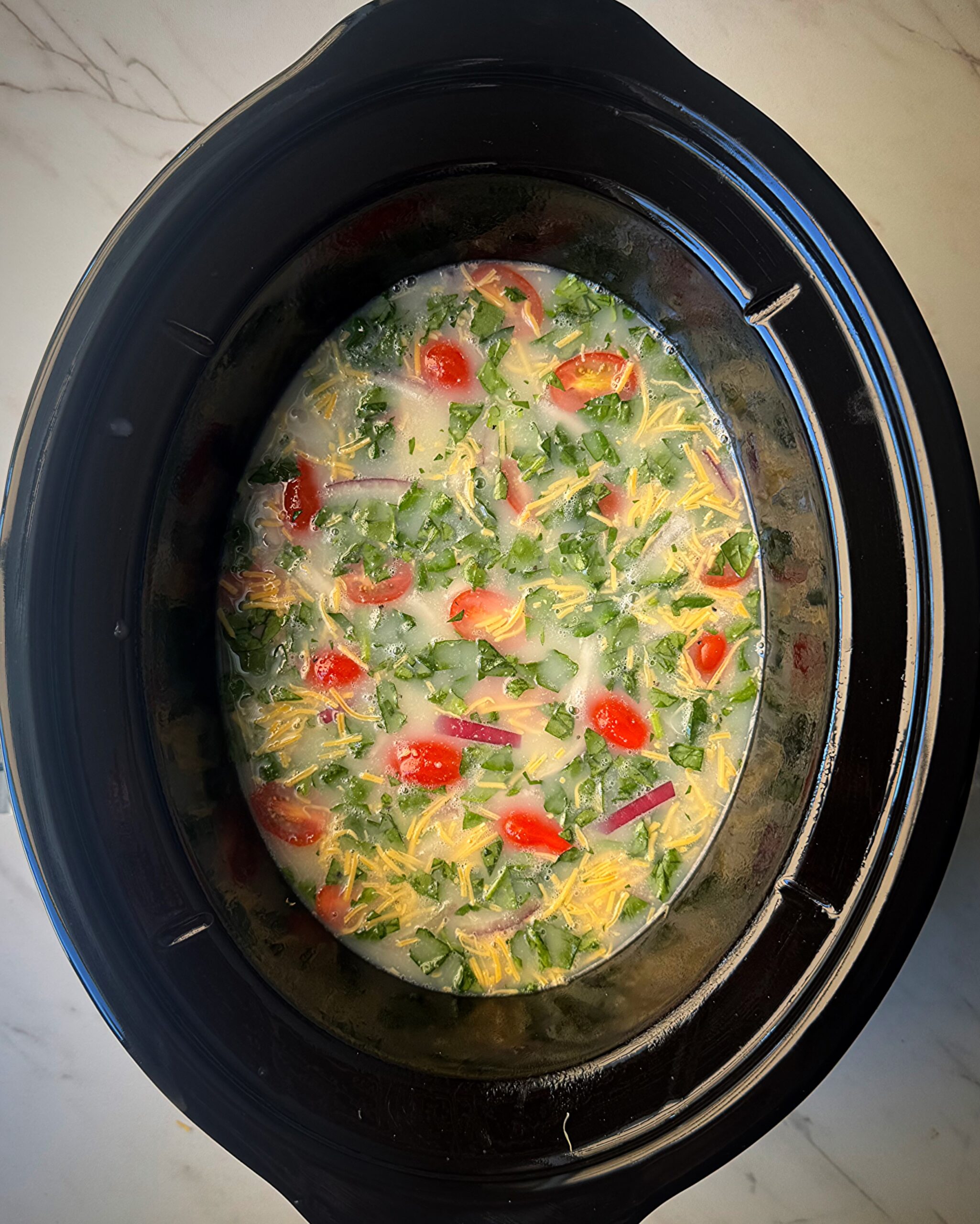 overhead shot of uncooked gg White Fritatta in a black slow cooker