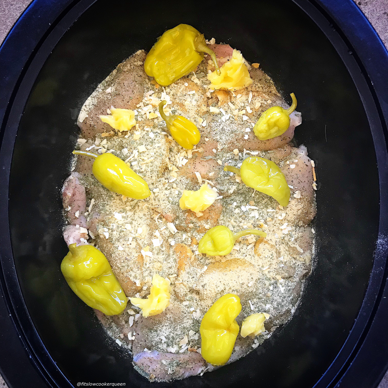 overhead side shot of uncooked Mississippi chicken in a black slow cooker