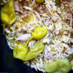 overhead side shot of cooked mississippi chicken in a black slow cooker