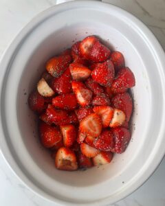 overhead shot of uncooked strawberry basil jam in a white slow cooker