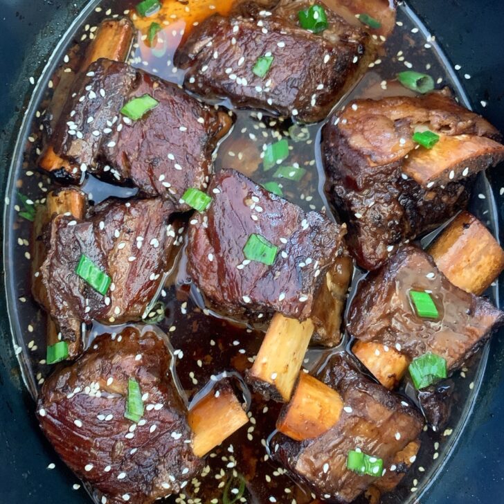 close up of korean style short ribs with sesame seeds and sliced green onions on top