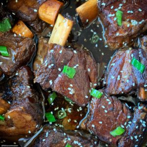 super close up shot of short ribs with sesame seeds and sliced green onions on top