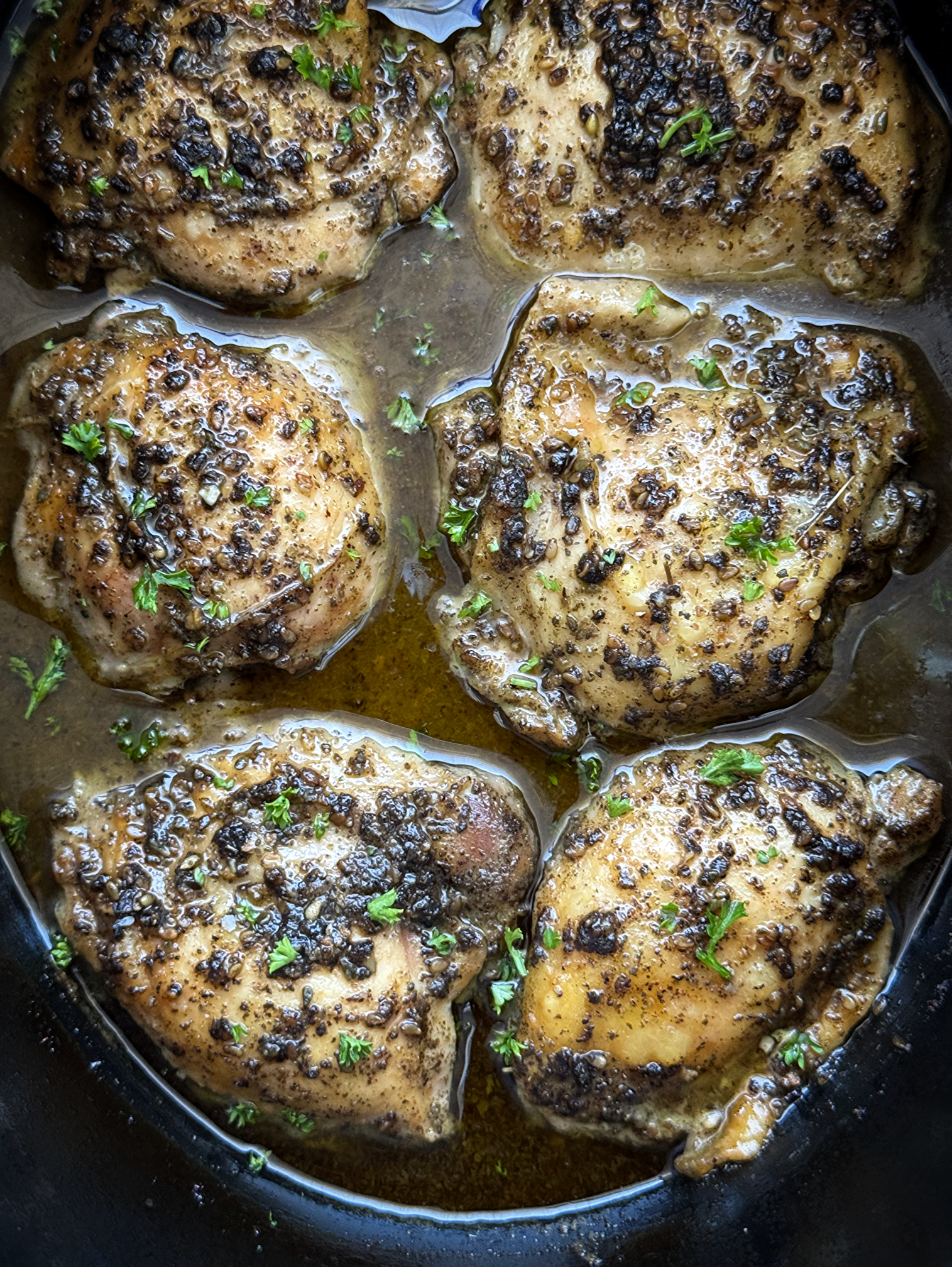 overhead close up shot of cooked zaatar chicken in a black slow cooker