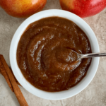 overhead shot of apple butter in a white bowl with a silver spoon