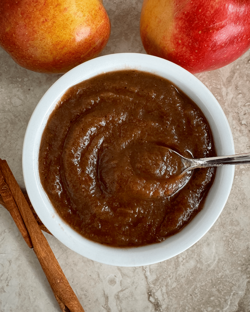 overhead shot of apple butter in a white bowl with a silver spoon