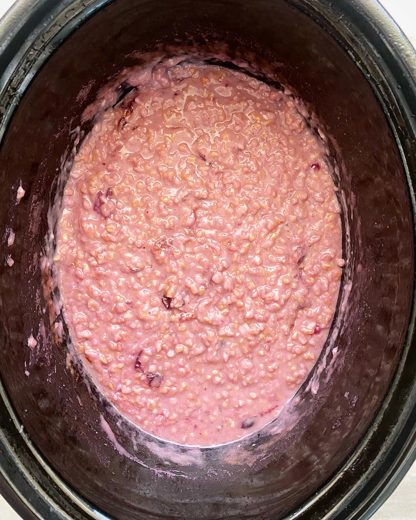 overhead shot of cooked berry oatmeal in a black slow cooker