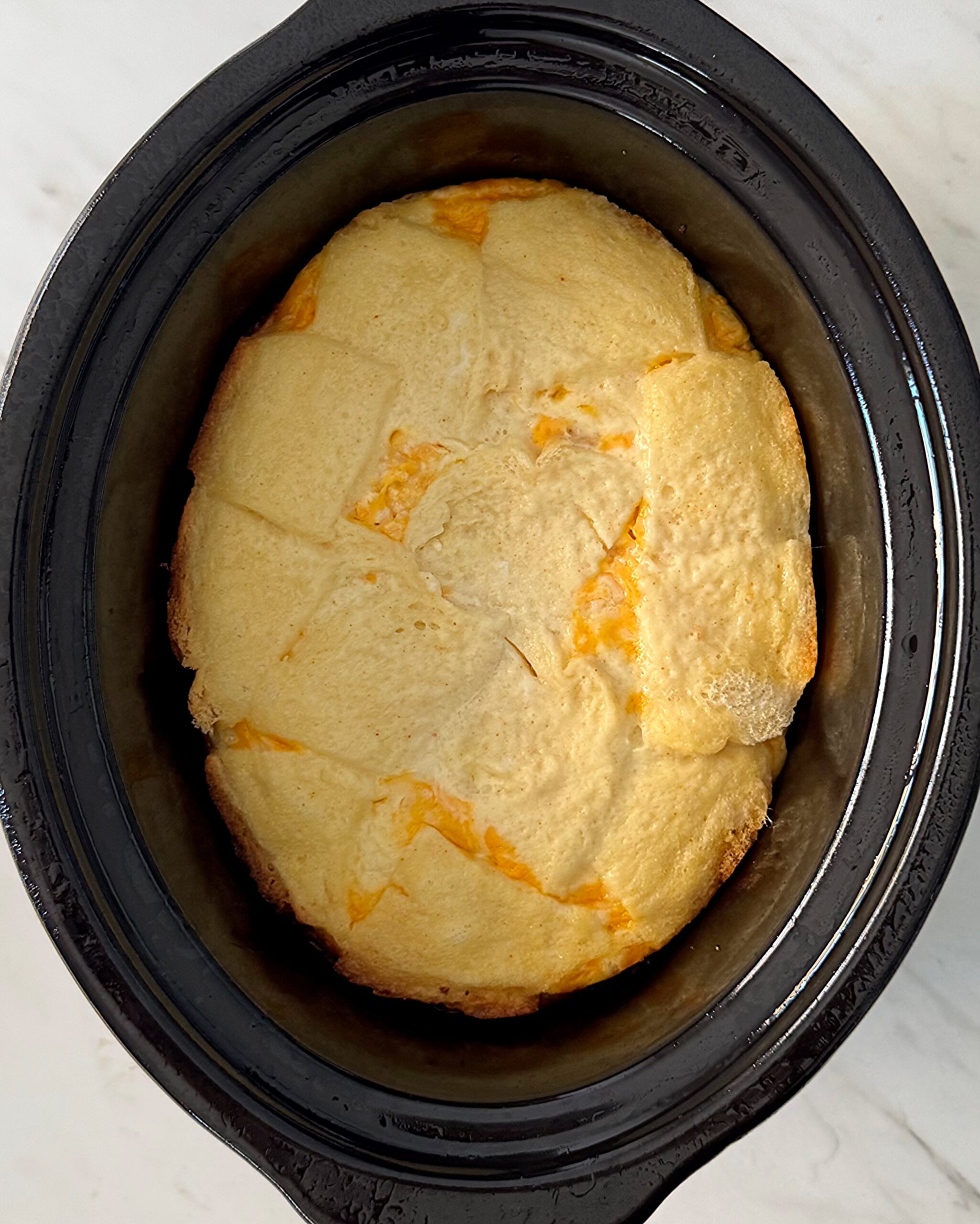 overhead shot of cooked overhead of Cheese Souffle in a black slow cooker