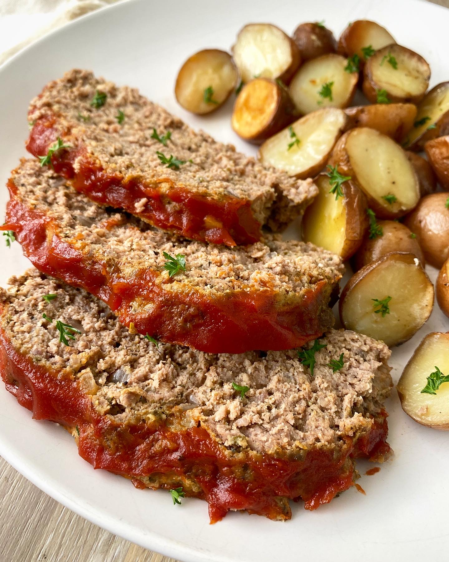 close up shot of meatloaf and potatoes on a white plate