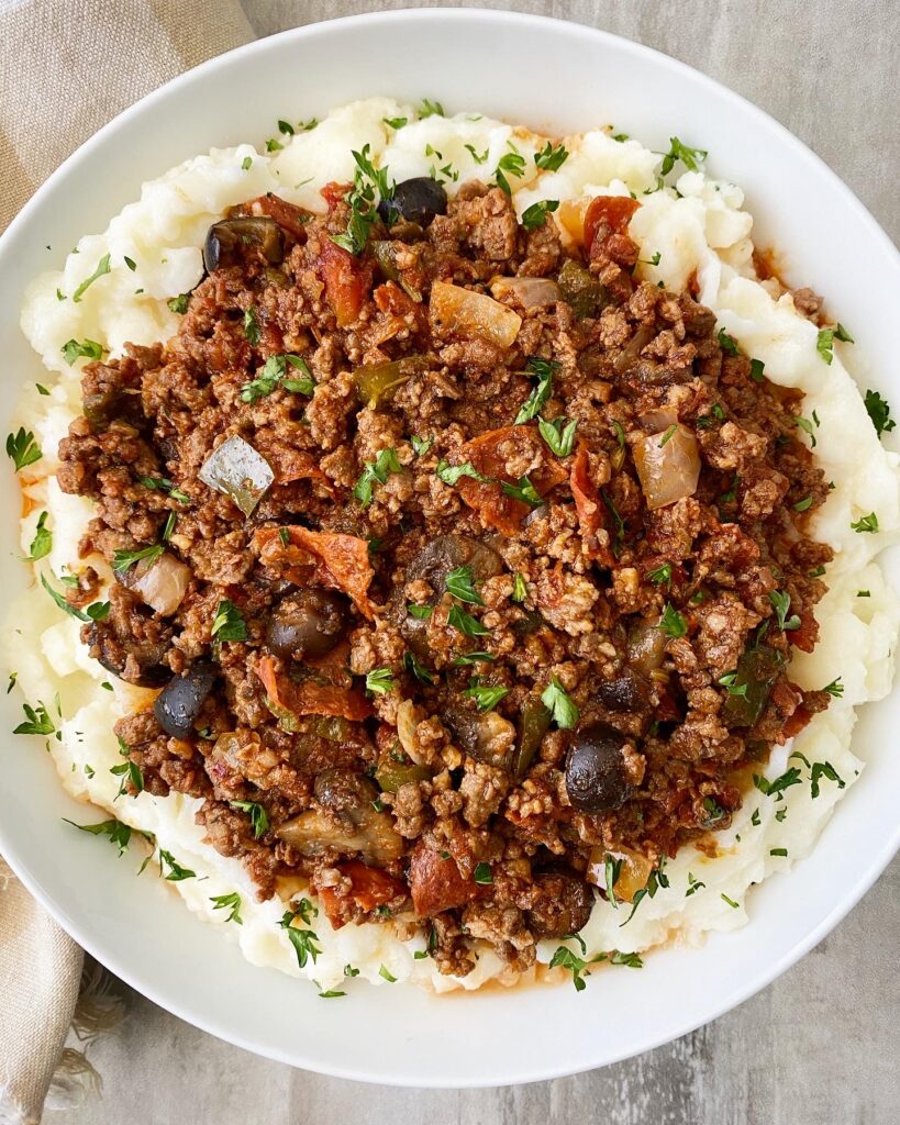 overhead shot of supreme pizza stew served over mashed potatoes