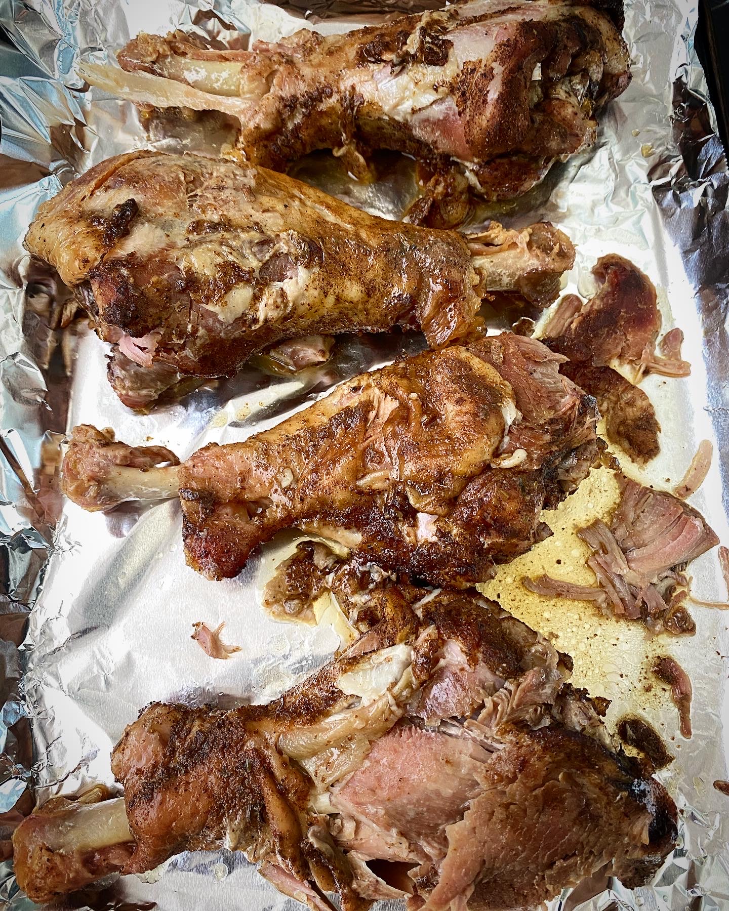 overhead shot of cooked turkey legs on a a foil lined baking sheet
