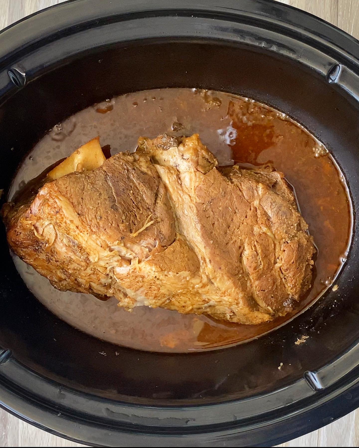overhead shot of cooked cuban mojo pork in a black slow cooker