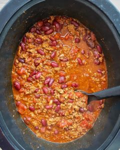 overhead shot of cooked beef chili in a black slow cooker